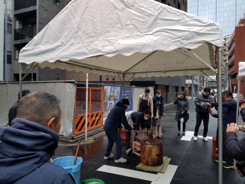 雨の中テント下で餅つき